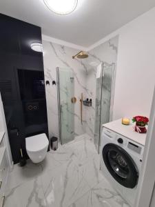 a bathroom with a shower and a washing machine at Modrzewiowy Zakątek in Augustów +15 photos