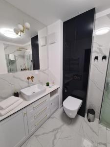 La salle de bains blanche est pourvue d'un lavabo et de toilettes. dans l'établissement Modrzewiowy Zakątek, à Augustów