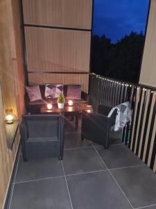 - un balcon avec deux chaises et une table avec des bougies dans l'établissement Modrzewiowy Zakątek, à Augustów