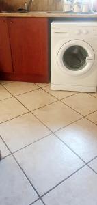 uma máquina de lavar roupa sentada num piso em azulejo numa cozinha em Sun view em Nelspruit