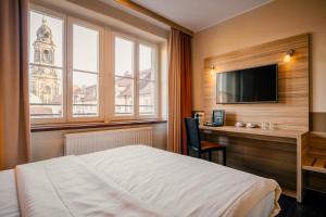 Cette chambre comprend un lit, un bureau et une télévision. dans l'établissement Star G Hotel Premium Dresden Altmarkt, à Dresde