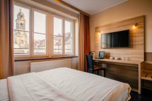 a hotel room with a bed and a desk and a television at Star G Hotel Premium Dresden Altmarkt in Dresden