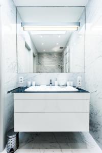 a white bathroom with a sink and a mirror at Magnifique Penthouse 3 chambres et terrasse sur l'Avenue Louise in Brussels