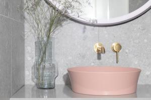 a bathroom with a pink bowl and a vase with flowers at Bob W Oosterpark in Amsterdam