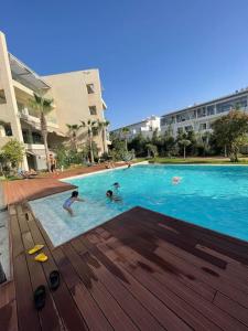a group of people swimming in a swimming pool at Superbe appartement à mohammadia in Mohammedia
