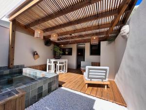 a patio with a hot tub and a wooden deck at Ti Kaloo, 2ème ligne, 40 m du Lagon in Saint-Leu