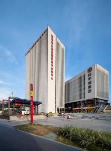 two tall buildings in a parking lot next to a street at Livetour Hotel Luogang Metro Guangzhou in Guangzhou