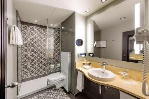 a bathroom with a sink and a toilet and a mirror at Mercure München City Center in Munich