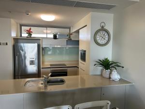 uma cozinha com um lavatório e um relógio na parede em Exclusive Apartment with Ocean Views em Caloundra