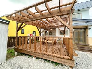a wooden pergola with a table on a deck at Cosmo St Inn Noboribetsu 3min walk from JR Noboribetsu st in Tomiura