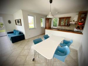cocina con mesa blanca y sillas azules en Villa Sunset Garden, en Siófok