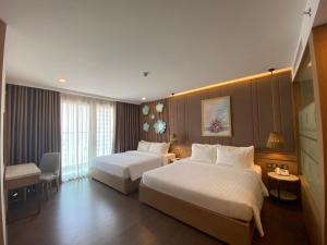 a hotel room with two beds and a chair at Virgo Hotel Nha Trang in Nha Trang