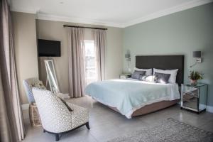 a bedroom with a bed and a chair and a television at The Whale on Main B&B in Hermanus