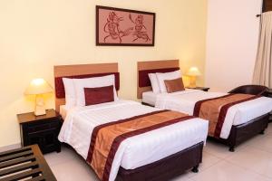 um quarto de hotel com duas camas e uma foto na parede em Sarinande Hotel em Seminyak
