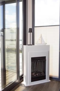 a white fireplace in a room with windows at Ostsee Hausboot Schleswig Ostseeblick 1 in Schleswig