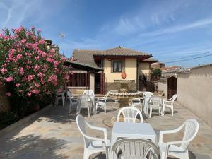 un patio con mesas y sillas blancas y flores rosas en Garrote Rivera, en Pereruela