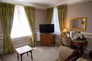 ein Hotelzimmer mit einem TV, einem Schreibtisch und einem Stuhl in der Unterkunft Cedars Inn by Greene King Inns in Barnstaple