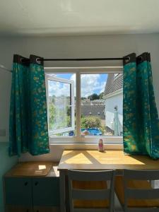Guest house Truro garden retreat في Kenwyn: نافذة ذات ستائر زرقاء وطاولة وكراسي