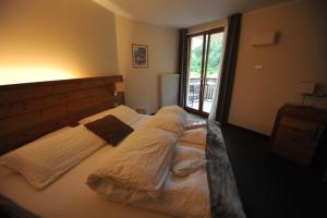 1 dormitorio con 2 camas con mantas y ventana en Bio Hotel Brusago Vital & Wellness, en Bedollo