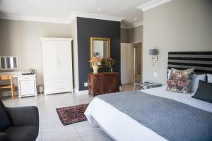 a bedroom with a bed and a desk and a chair at The Whale on Main B&B in Hermanus