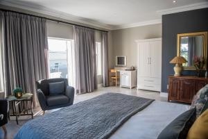 a bedroom with a bed and a chair and a window at The Whale on Main B&B in Hermanus