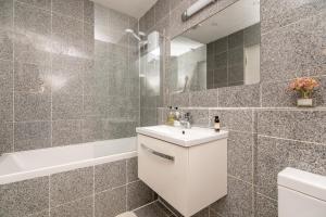 a bathroom with a white sink and a bath tub at Stunning Central 2BR Flat btw Soho & Covent Garden in London