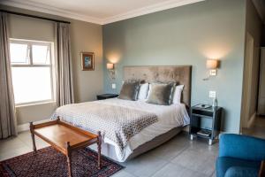 a bedroom with a bed and a table and a couch at The Whale on Main B&B in Hermanus