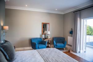 a bedroom with two blue chairs and a bed at The Whale on Main B&B in Hermanus