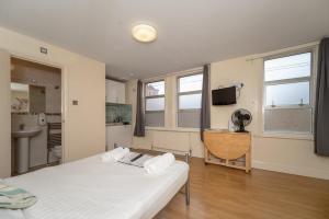a bedroom with a bed and a sink and two windows at Flexistay Aparthotel Tooting in London