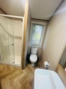 ein Bad mit einem WC und einer Glasdusche in der Unterkunft Treetops Lodge with Hot Tub in York