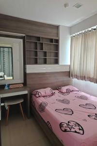 雅加達的住宿－MyStayPro Sentra Timur，一间卧室配有一张粉红色的床、一张桌子和一个窗户。