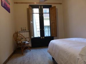 1 dormitorio con cama, ventana y silla en Apartamento Ábside de San Juan II, en Estella