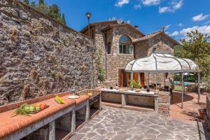 a stone building with a table and an umbrella at PODERE MONTIONI 6&2, Emma Villas in Rapolano Terme
