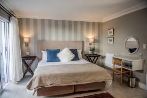 a bedroom with a bed with blue and white pillows at The Whale on Main B&B in Hermanus