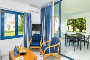 a living room with blue chairs and a table at Helion Resort in Gouvia
