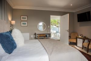 a bedroom with a large white bed and a window at The Whale on Main B&B in Hermanus