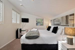 a white bedroom with a large bed and a television at Snow Stream 3 Bedroom and loft with gas fire garage parking and balcony in Thredbo