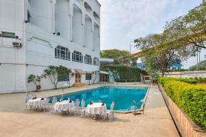 uma piscina com mesas e cadeiras ao lado de um edifício em The Pride Hotel, Nagpur em Nagpur