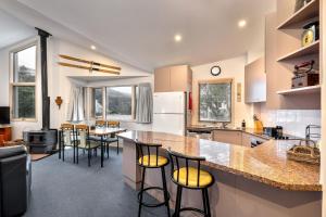 a kitchen with a counter and some chairs in it at Lhotsky 2 Bedroom with fireplace and sweeping mountain view in Thredbo