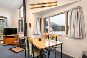 uma sala de jantar com mesa, cadeiras e janelas em Lhotsky 2 Bedroom with fireplace and sweeping mountain view em Thredbo