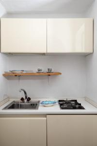 羅通多港的住宿－Casa Neva by Wonderful Italy，白色的厨房设有水槽和炉灶。