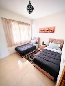 um quarto com 2 camas e uma janela em The blue pearl-Sensational beach apartment in Aourir em Agadir