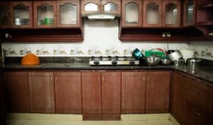 a kitchen with wooden cabinets and a counter top at 4BR AC House near Edappally Lulu Mall & AIMS Kochi in Ernakulam