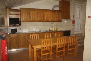 a kitchen with wooden cabinets and a wooden table and chairs at CasaTioManel in Amiães de Baixo