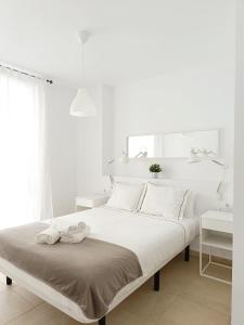 una camera da letto bianca con un letto e asciugamani di SHERRY SUITES V Apartamentos PARKING GRATUITO a Jerez de la Frontera