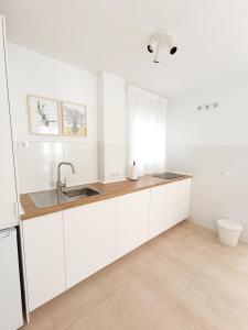 a kitchen with white cabinets and a sink at SHERRY SUITES V Apartamentos PARKING GRATUITO in Jerez de la Frontera