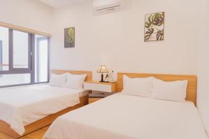 2 Betten in einem Zimmer mit Fenster in der Unterkunft OYO 1192 Victory Hotel Dien Ban in Đà Nẵng