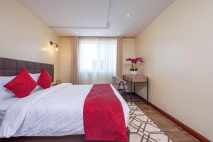 sypialnia z dużym łóżkiem z czerwonymi poduszkami w obiekcie Roma Court Serviced Apartments w mieście Nairobi