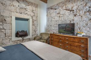 ein Schlafzimmer mit einer Steinmauer, einem Bett und einer Kommode in der Unterkunft La Tabarchina - Carloforte Lovely Apt With Terrace! in Carloforte
