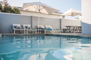 a swimming pool with chairs and an umbrella at The Whale on Main B&B in Hermanus